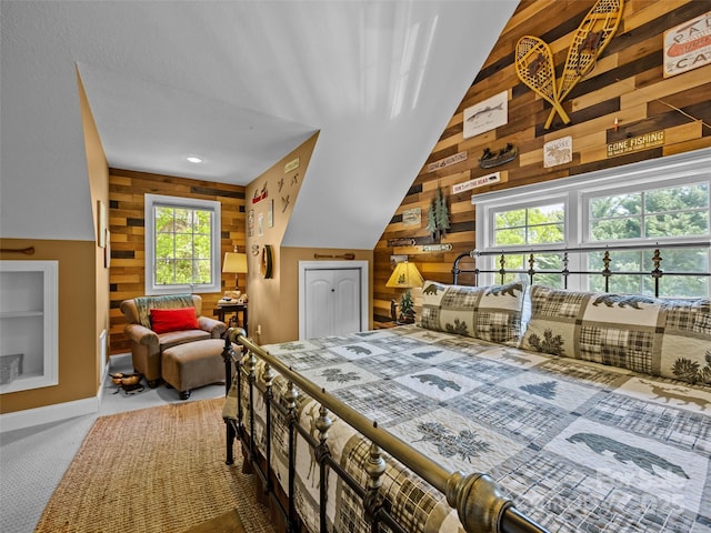 bedroom with baseboards, carpet, wood walls, and lofted ceiling
