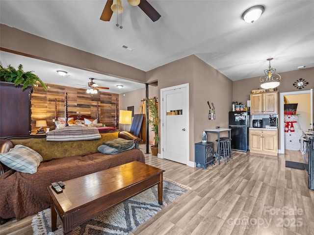 living room with a ceiling fan, baseboards, visible vents, and light wood-type flooring