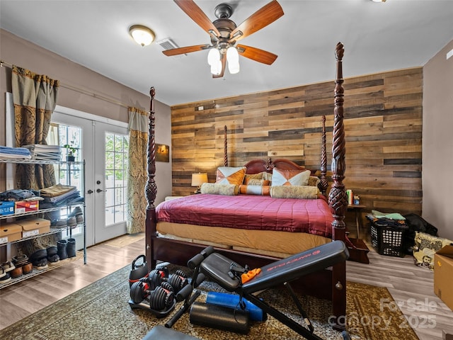 bedroom with access to outside, french doors, wood walls, and wood finished floors