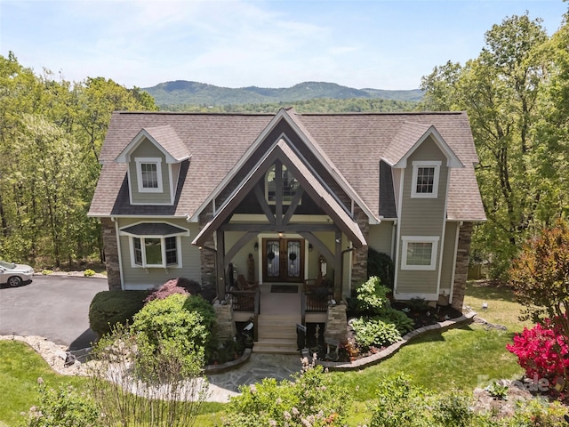 view of front of house with french doors, a mountain view, a porch, and roof with shingles