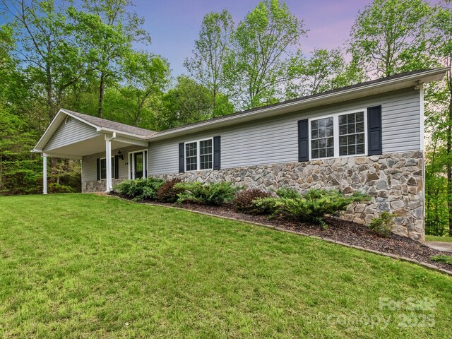ranch-style house with a porch, a front yard, and stone siding