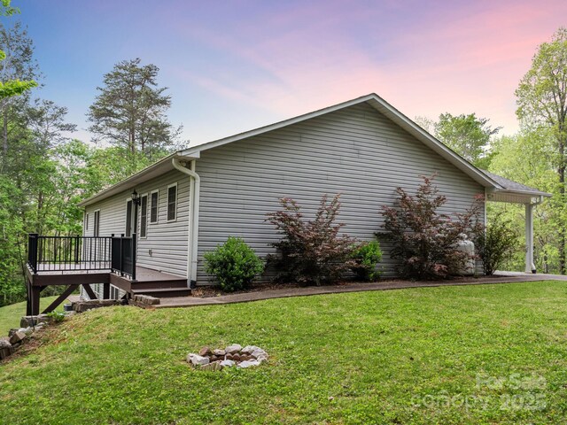 view of property exterior with a lawn and a wooden deck