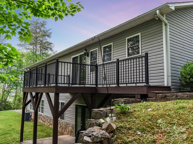 rear view of property with a lawn, cooling unit, and a wooden deck