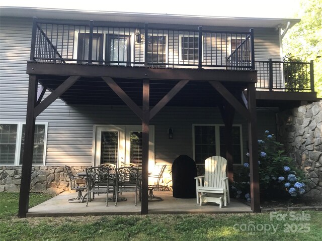 back of house featuring a patio area, a balcony, and stone siding