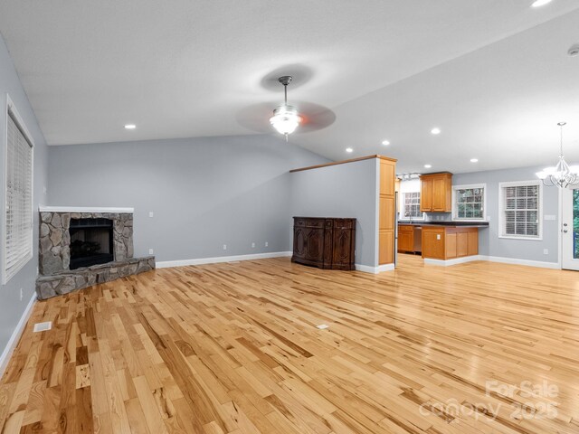 unfurnished living room featuring light wood-type flooring, recessed lighting, baseboards, and a stone fireplace