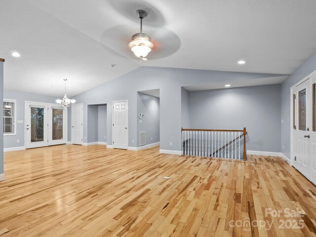 unfurnished living room featuring baseboards, vaulted ceiling, light wood-type flooring, and visible vents