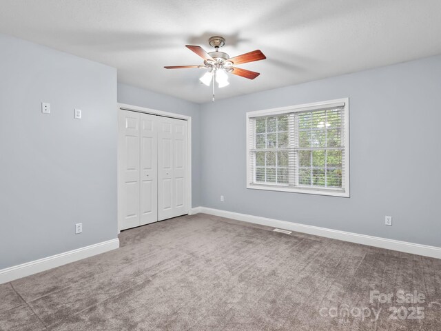 unfurnished bedroom with a closet, baseboards, ceiling fan, and carpet flooring