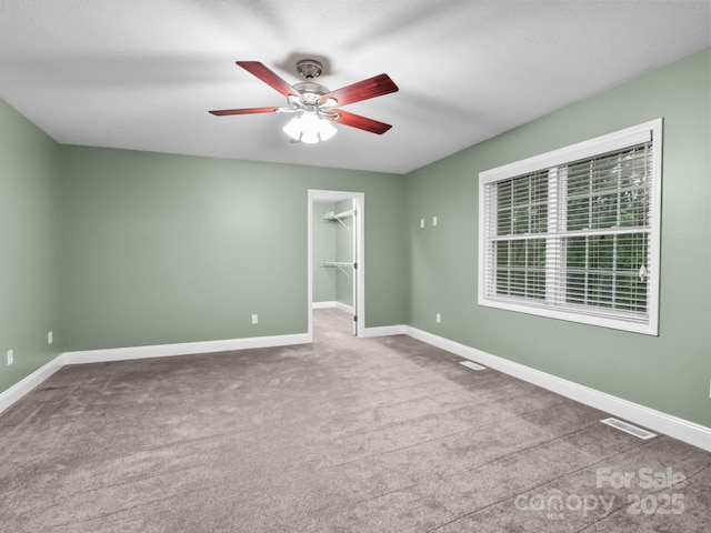 unfurnished bedroom with a spacious closet, baseboards, carpet, and visible vents