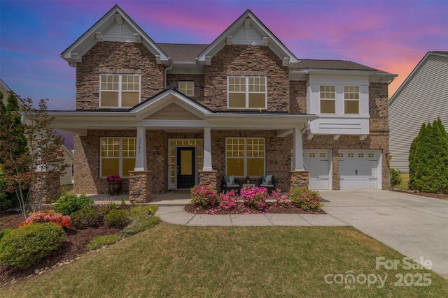 craftsman inspired home featuring a porch, driveway, a lawn, a garage, and stone siding