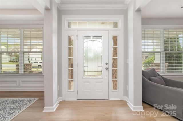 entrance foyer with ornamental molding and wood finished floors