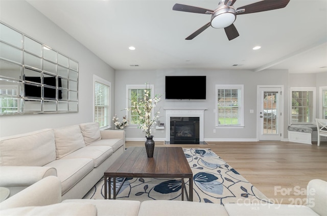 living area with a fireplace with flush hearth, baseboards, recessed lighting, and wood finished floors