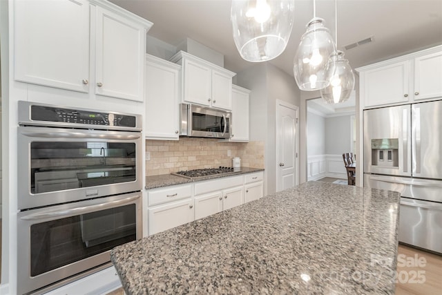 kitchen with visible vents, light stone counters, white cabinets, and stainless steel appliances