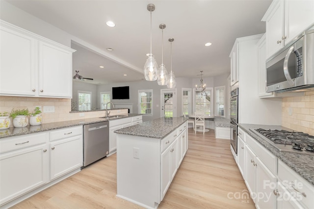 kitchen with a kitchen island, stainless steel appliances, white cabinets, and a sink