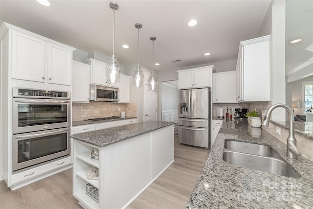 kitchen with stainless steel appliances, tasteful backsplash, a sink, and a center island