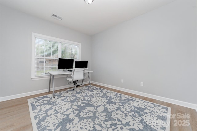 office space with baseboards, visible vents, and wood finished floors