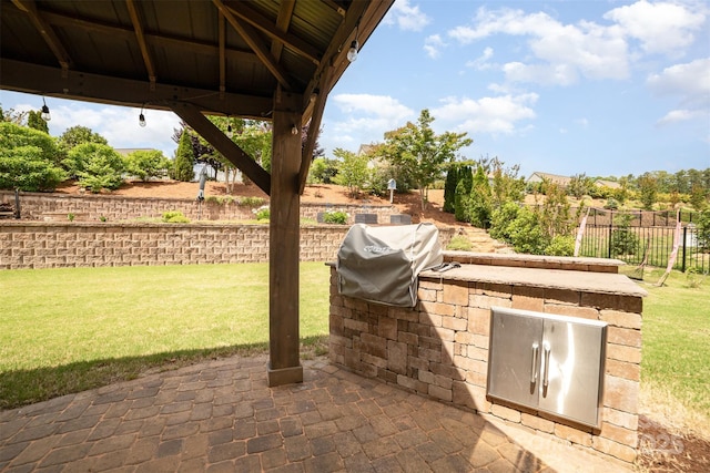 view of patio featuring fence, a grill, and exterior kitchen