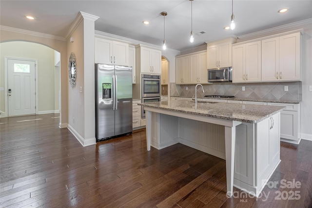kitchen featuring stainless steel appliances, arched walkways, ornamental molding, and a sink
