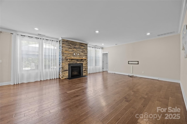 unfurnished living room with visible vents, ornamental molding, wood finished floors, a fireplace, and baseboards