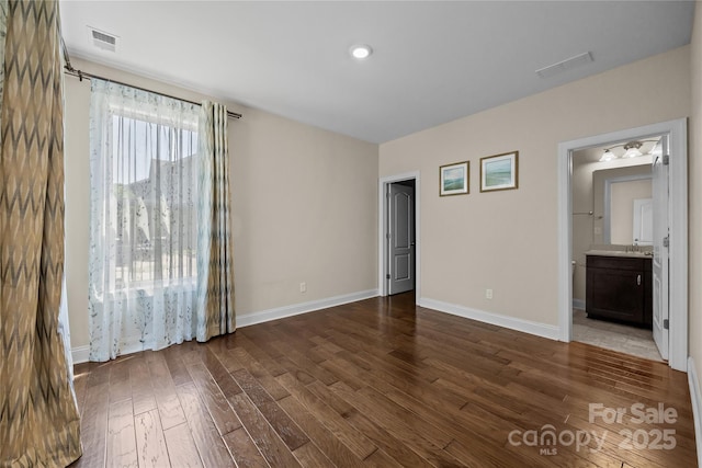 unfurnished bedroom featuring visible vents, baseboards, and dark wood-type flooring