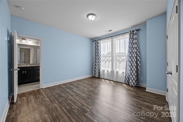 unfurnished bedroom featuring baseboards, visible vents, and dark wood-type flooring