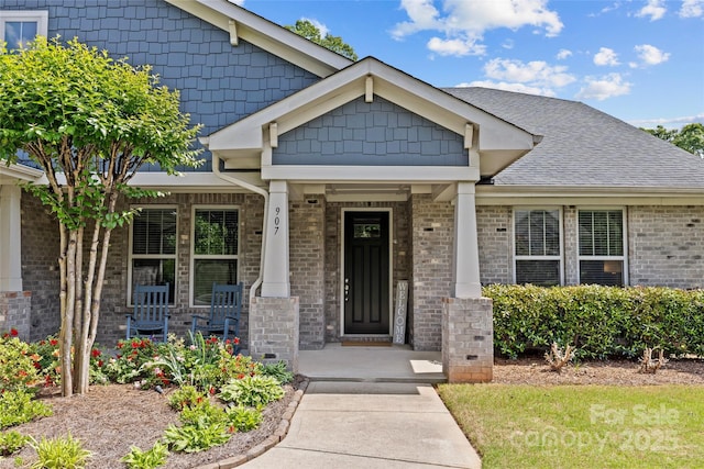 doorway to property with covered porch and brick siding