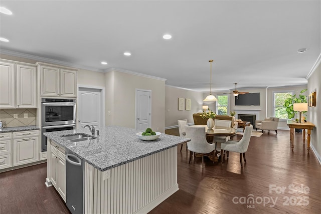 kitchen with ornamental molding, a fireplace, dark wood-style floors, a sink, and stainless steel appliances