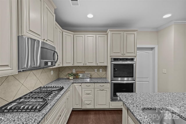 kitchen with light stone countertops, appliances with stainless steel finishes, dark wood finished floors, and visible vents