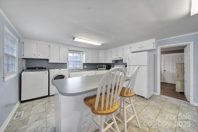 kitchen with visible vents, freestanding refrigerator, baseboards, stainless steel microwave, and washing machine and clothes dryer