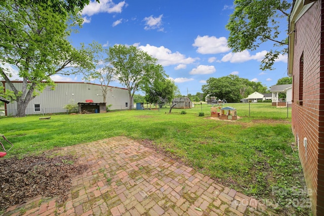 view of yard with a patio, fence, and an outbuilding