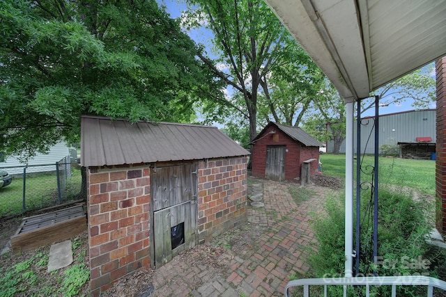 view of patio / terrace featuring an outbuilding, fence, and a storage shed