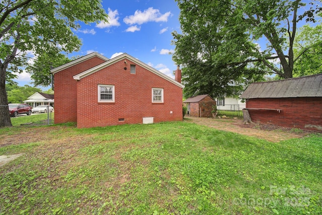 view of home's exterior featuring fence, a chimney, brick siding, crawl space, and a lawn