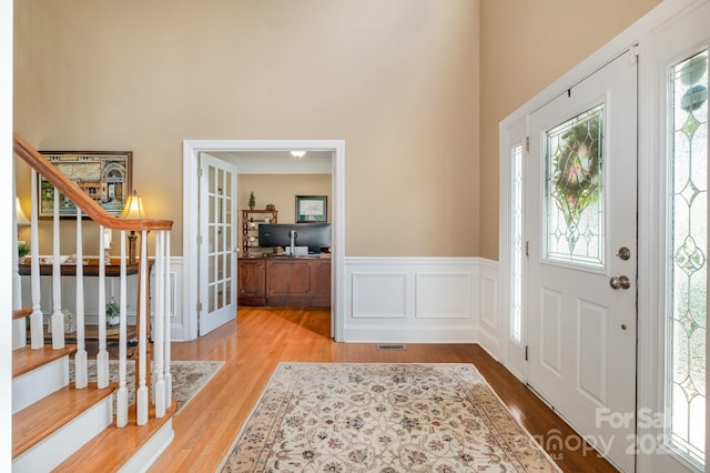 7730 Windsor Forest Pl, Harrisburg, NC 28075 - entrance foyer featuring stairs, french doors, wood finished floors, wainscoting, and a high ceiling