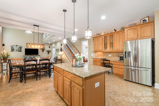 7730 Windsor Forest Pl, Harrisburg, NC 28075 - kitchen with light tile patterned floors, light stone counters, stainless steel refrigerator with ice dispenser, a kitchen island, and tasteful backsplash