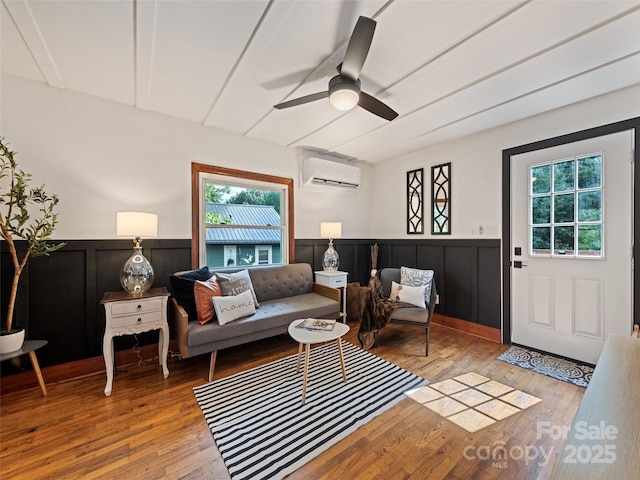 68 Piney Mountain Church Rd, Candler, NC 28715 - living area with wood-type flooring, an AC wall unit, ceiling fan, and wainscoting