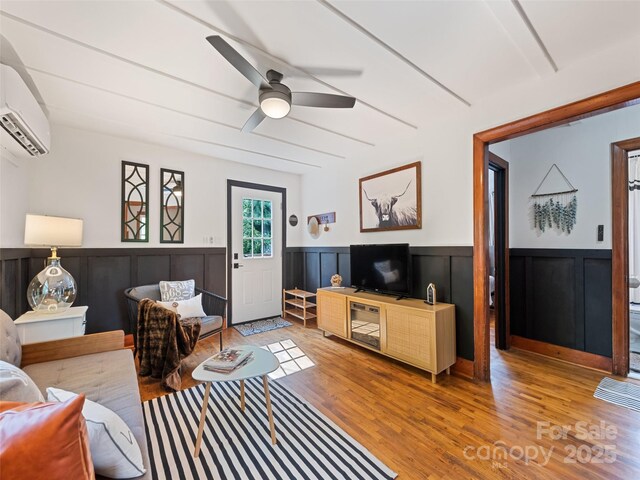 68 Piney Mountain Church Rd, Candler, NC 28715 - living room featuring an AC wall unit, a ceiling fan, wood finished floors, and a wainscoted wall