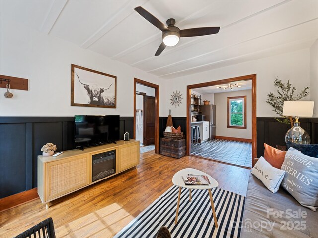 68 Piney Mountain Church Rd, Candler, NC 28715 - living area with a wainscoted wall, ceiling fan, beamed ceiling, and light wood-type flooring