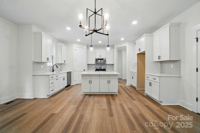 kitchen featuring recessed lighting, a chandelier, tasteful backsplash, a sink, and stainless steel appliances