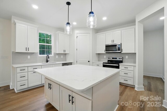 kitchen with a kitchen island, white cabinetry, a sink, backsplash, and stainless steel appliances
