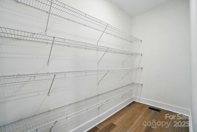 spacious closet featuring dark wood finished floors and visible vents