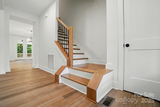 stairs with baseboards, visible vents, and wood finished floors