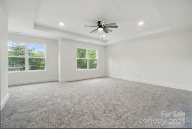 empty room featuring recessed lighting, a raised ceiling, ceiling fan, and a wealth of natural light