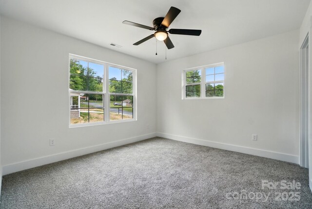 carpeted empty room featuring baseboards, ceiling fan, and visible vents
