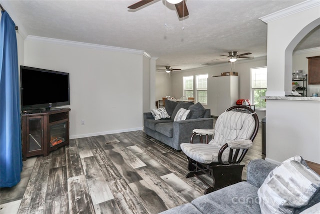 living area featuring crown molding, arched walkways, a ceiling fan, baseboards, and wood finished floors