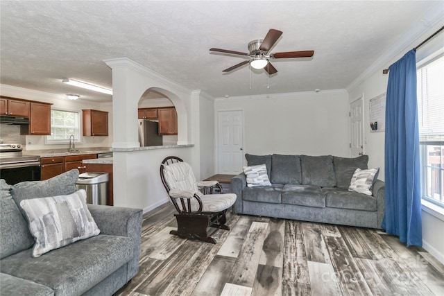 living room featuring baseboards, ceiling fan, ornamental molding, and wood finished floors