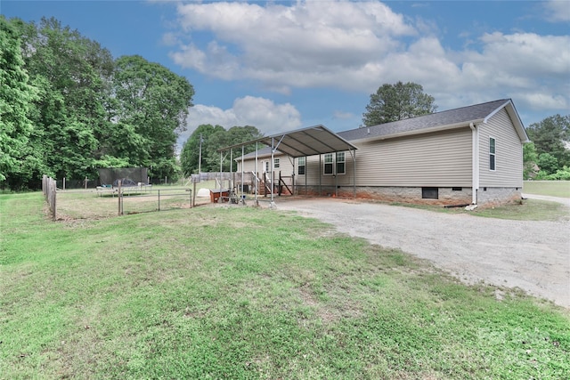 back of house featuring a detached carport, fence, dirt driveway, crawl space, and a yard