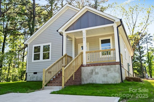 bungalow-style home featuring covered porch, board and batten siding, and a front lawn