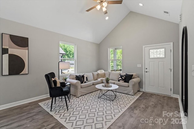 living area featuring ceiling fan, high vaulted ceiling, a wealth of natural light, wood finished floors, and visible vents