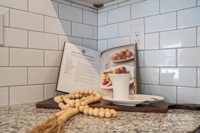 interior details featuring decorative backsplash, white cabinetry, and light stone countertops