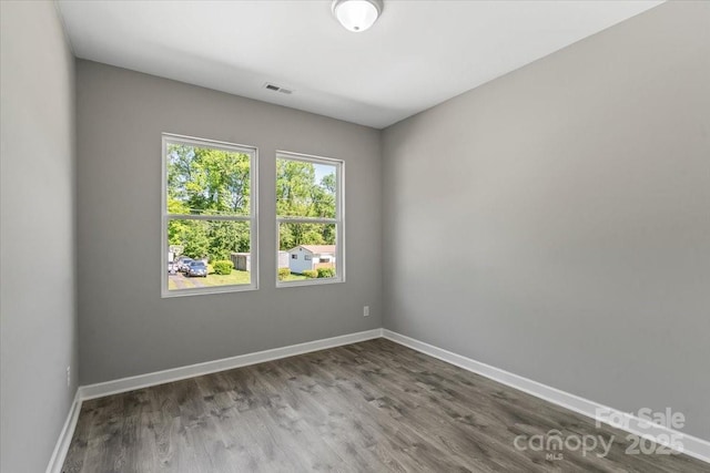spare room with baseboards, wood finished floors, and visible vents