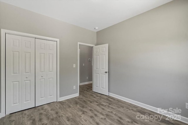 unfurnished bedroom with baseboards, a closet, and wood finished floors